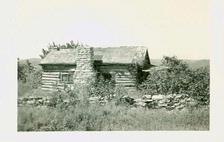 From the Library collection, on back is written "On road toward Branson.  House is gone now. Typical log house." No date given.